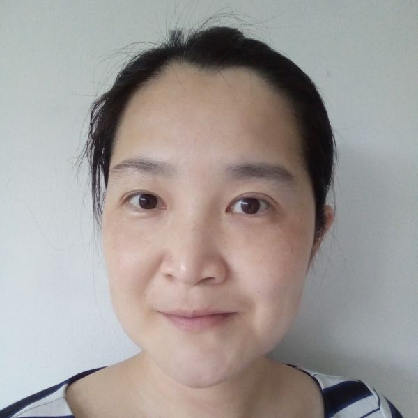 Close-up portrait of an Asian woman with dark hair pulled back, neutral expression, wearing a striped top against a light wall.